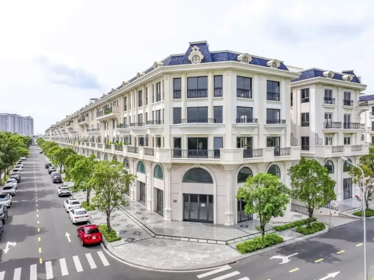 Dãy shophouse The Legend Vạn Phúc City với mái dốc xanh than có cửa sổ mái, mặt tiền trắng nhiều ô cửa vòm và hàng ô tô đỗ dọc đường