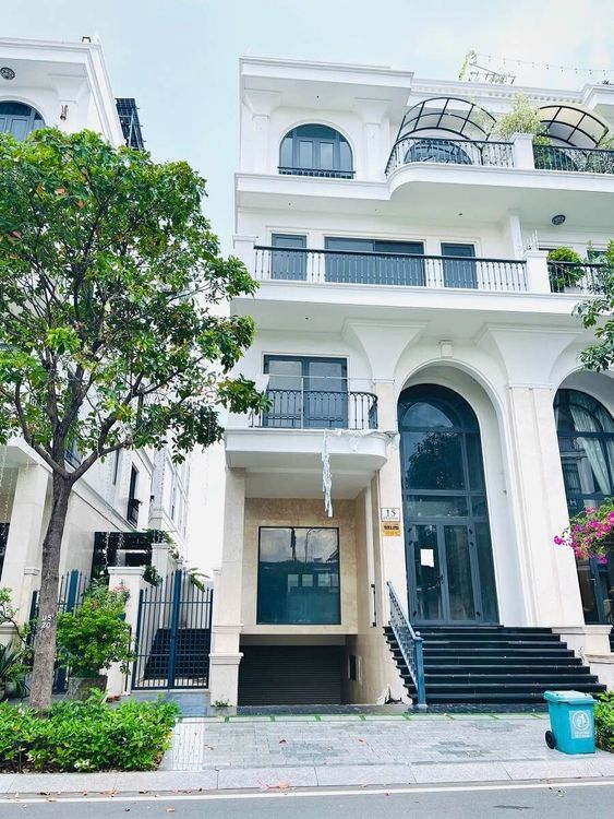 Mặt tiền nhà phố ngang 9 m kiến trúc tân cổ điển màu trắng ở Vạn Phúc City với cửa vòm cao, bậc thềm đá đen và ban công có mái kính
