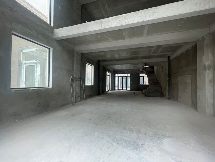 Tầng trệt căn nhà phố ngang 9 m còn thô ở Vạn Phúc City, sàn bê tông trống suốt từ cửa trước tới cuối nhà, cầu thang bê tông và ô cửa sổ bên hông