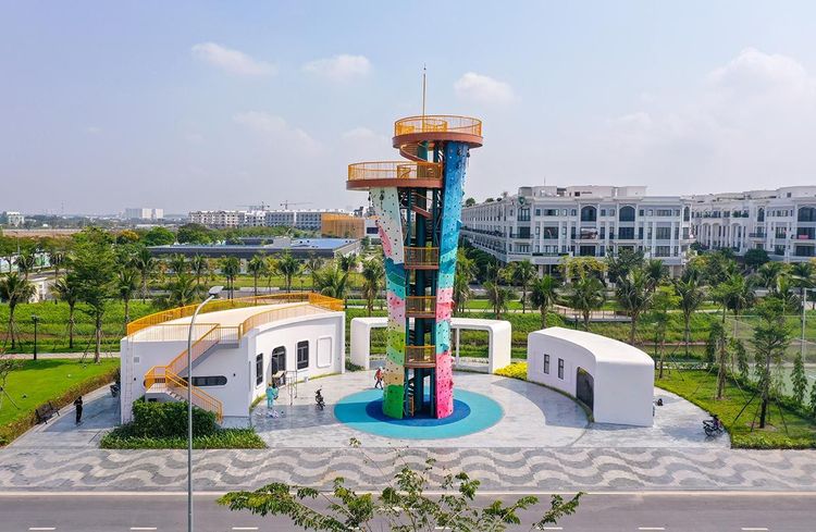 Tháp leo núi nhân tạo nhiều màu cao khoảng 17 m bên cạnh hai khối nhà trắng và quảng trường lát gạch trong Vạn Phúc City