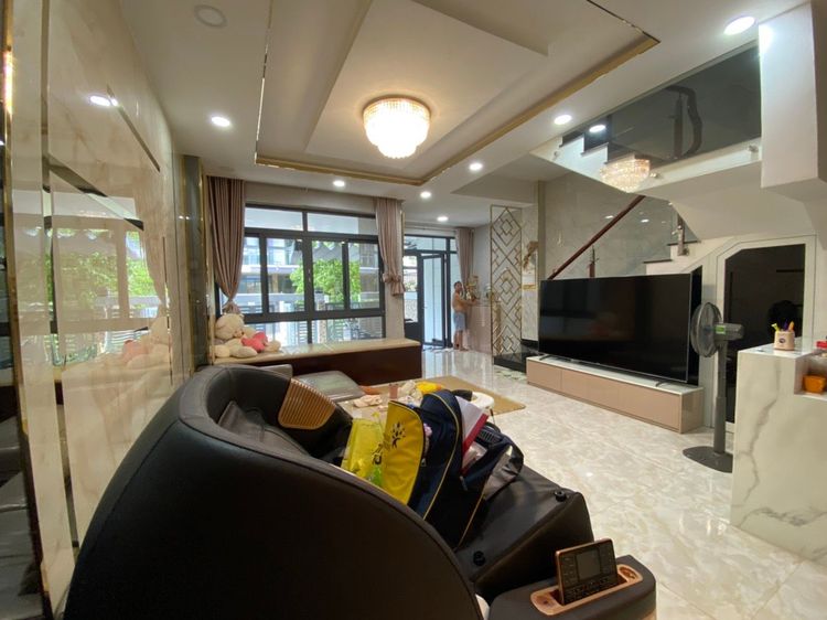 Phòng khách căn nhà phố 6x17 m hoàn thiện với sofa, tivi, đèn trần và cửa kính nhìn ra sân trước
