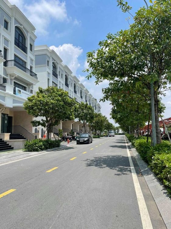 Đường nội khu rộng có vạch kẻ, hai bên là dãy nhà phố và hàng cây xanh tại khu Đông Nam Vạn Phúc City