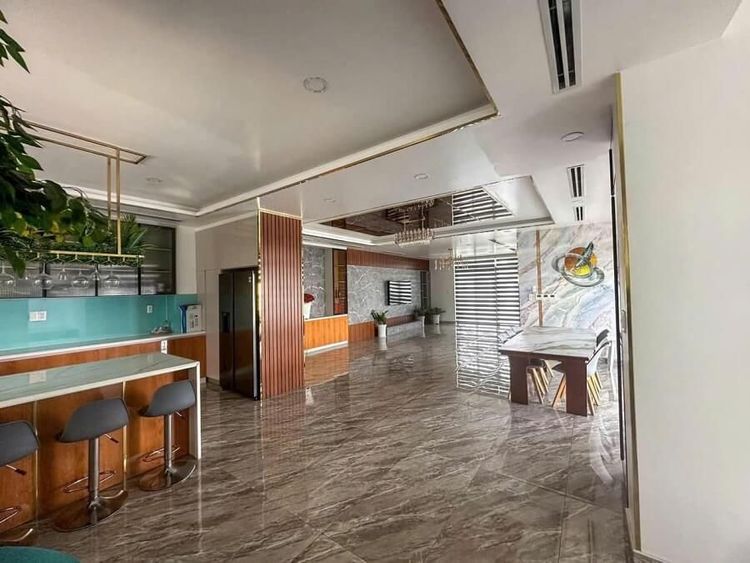 Không gian tầng trệt một căn góc 13x22 m đã hoàn thiện, có quầy bar bếp và sàn đá tại Vạn Phúc City