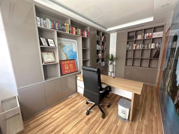Phòng làm việc trong căn nhà phố góc 13x22 m Vạn Phúc City với bàn gỗ, ghế lưng cao màu đen, tủ sách âm tường và sàn gỗ