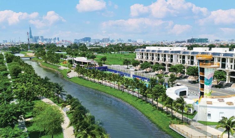 Ảnh thực tế kênh Sông Trăng uốn qua hàng dừa và sân thể thao, tháp leo núi nhiều màu, xa xa là Landmark 81