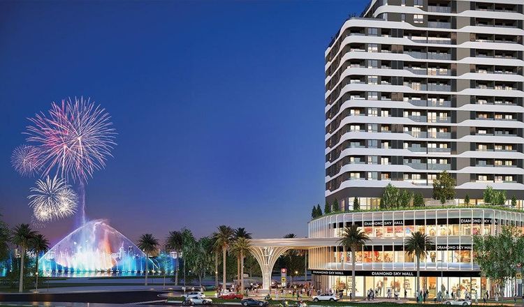Phối cảnh tháp Diamond Sky về đêm với khối đế Diamond Sky Mall cạnh quảng trường nhạc nước đang phun nước và bắn pháo hoa