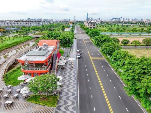 Nhà hàng Sugar Town màu cam đỏ bên kênh Sông Trăng, cạnh đường nội khu rộng và bàn ghế ngoài trời