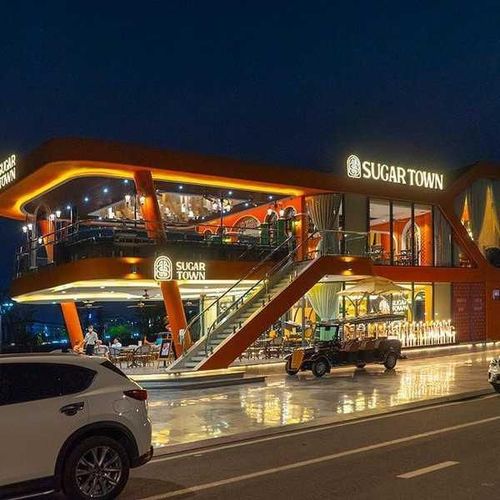 Mặt tiền nhà hàng Sugar Town hai tầng lên đèn vào buổi tối, có cầu thang ngoài trời và khu bàn ghế tầng trệt